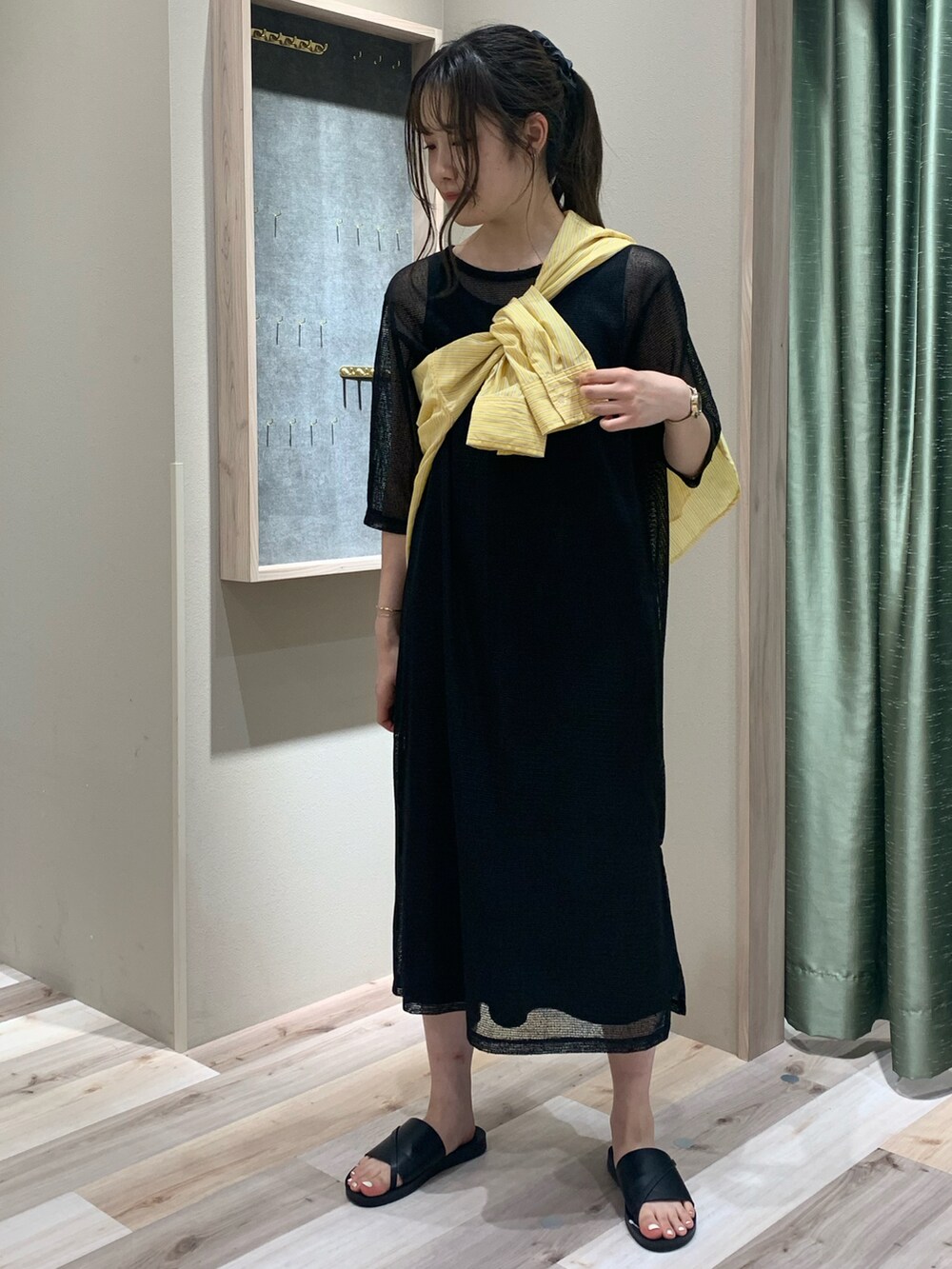 イエロー系のシャツ/ブラウス、ブラック系のワンピース、ブラック系のサンダルを着用したレディースの春コーディネートの2枚目の写真