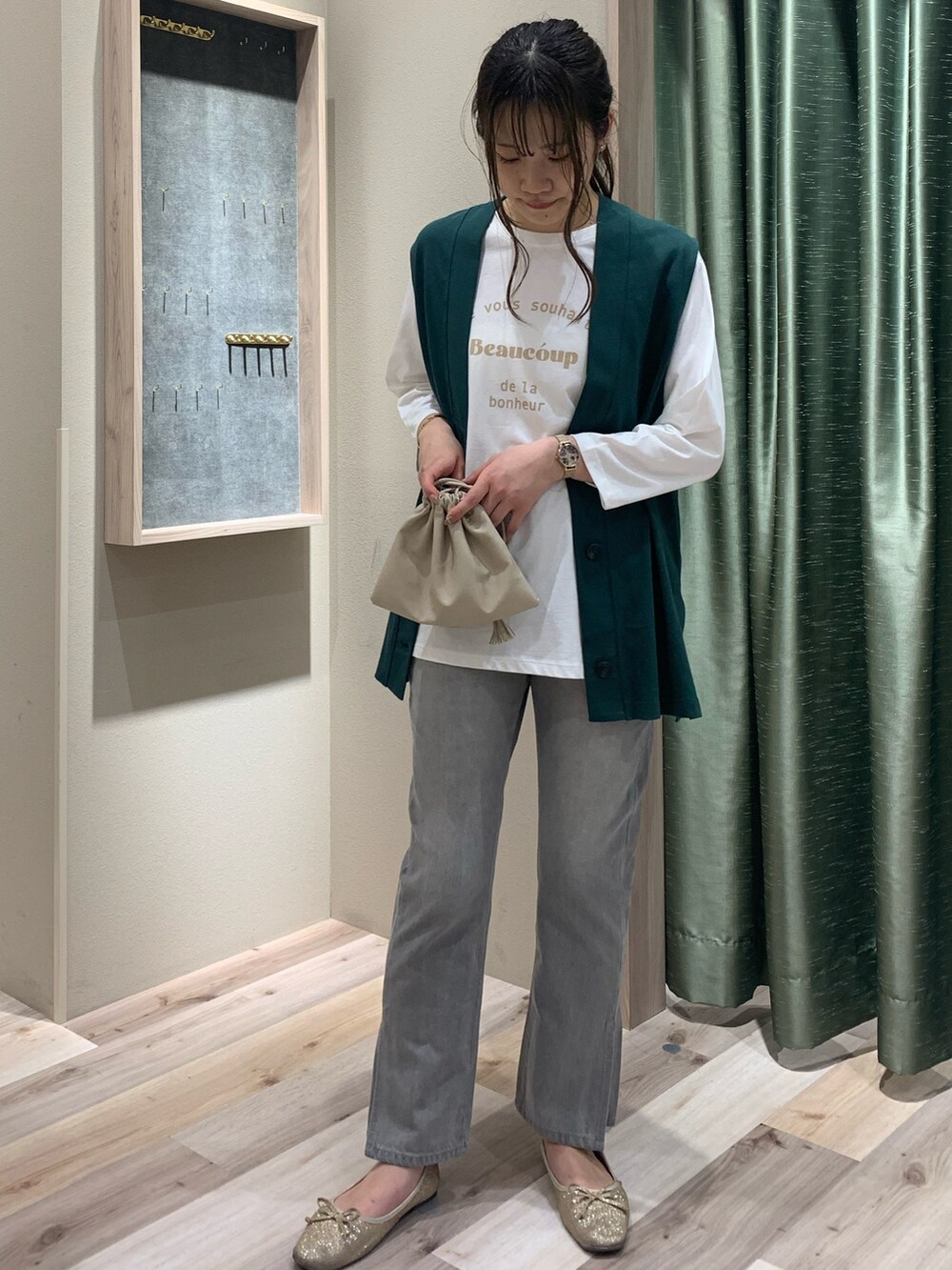 グリーン系のベスト、ホワイト系のTシャツ/カットソー、ベージュ系のショルダーバッグを着用したレディースの春コーディネートの2枚目の写真