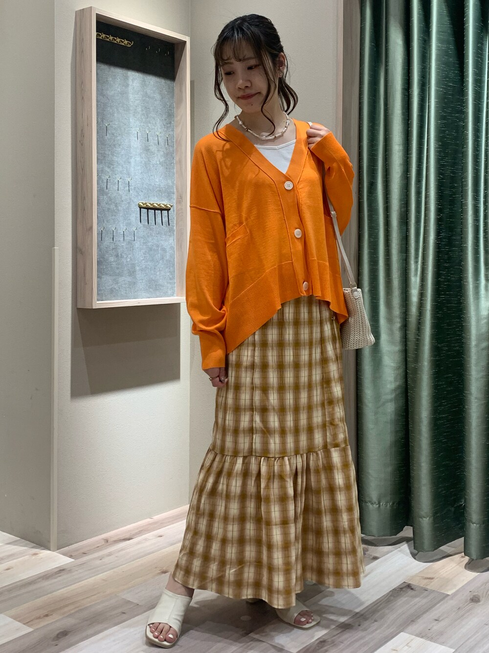 ホワイト系のキャミソール、オレンジ系のカーディガン/ボレロ、ベージュ系のスカートを着用したレディースの春コーディネートの2枚目の写真