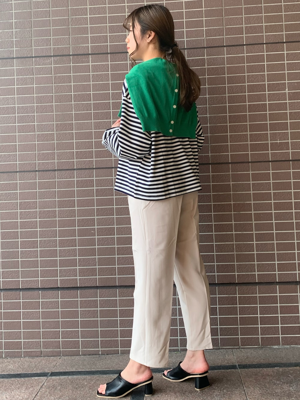 グリーン系のカーディガン/ボレロ、ブルー系のTシャツ/カットソー、ホワイト系のスラックスを着用したレディースの春コーディネートの3枚目の写真