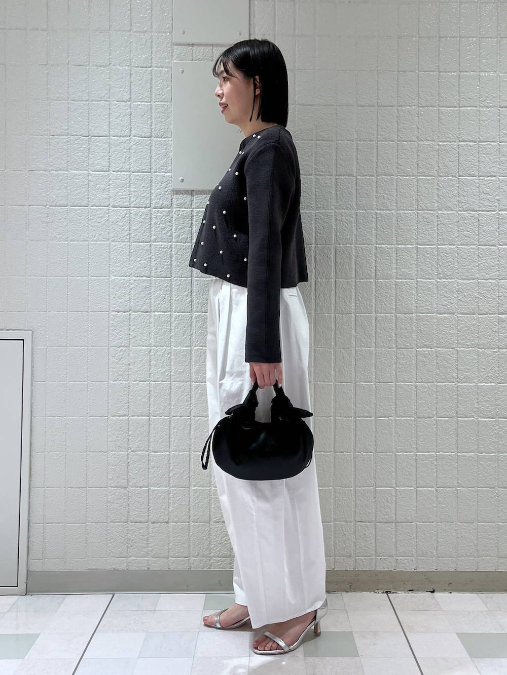 グレー系のカーディガン/ボレロ、シルバー系のサンダル、ブラック系のショルダーバッグを着用したレディースの春コーディネートの2枚目の写真