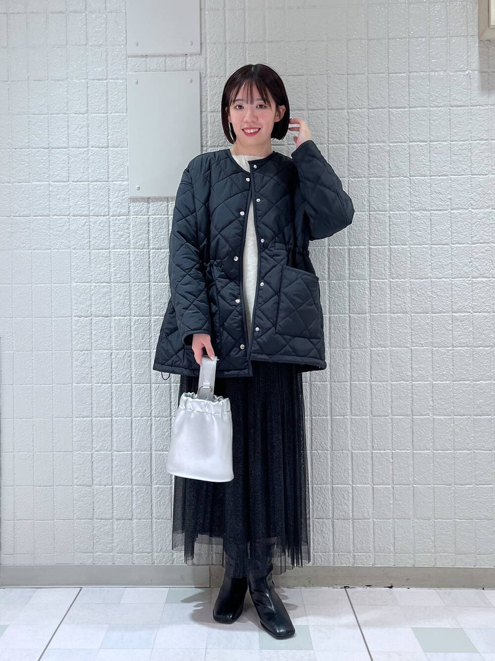 ブラック系のスカート、ブラック系のダウンジャケット/コート、ホワイト系のニット/セーターを着用したレディースの冬コーディネートの4枚目の写真