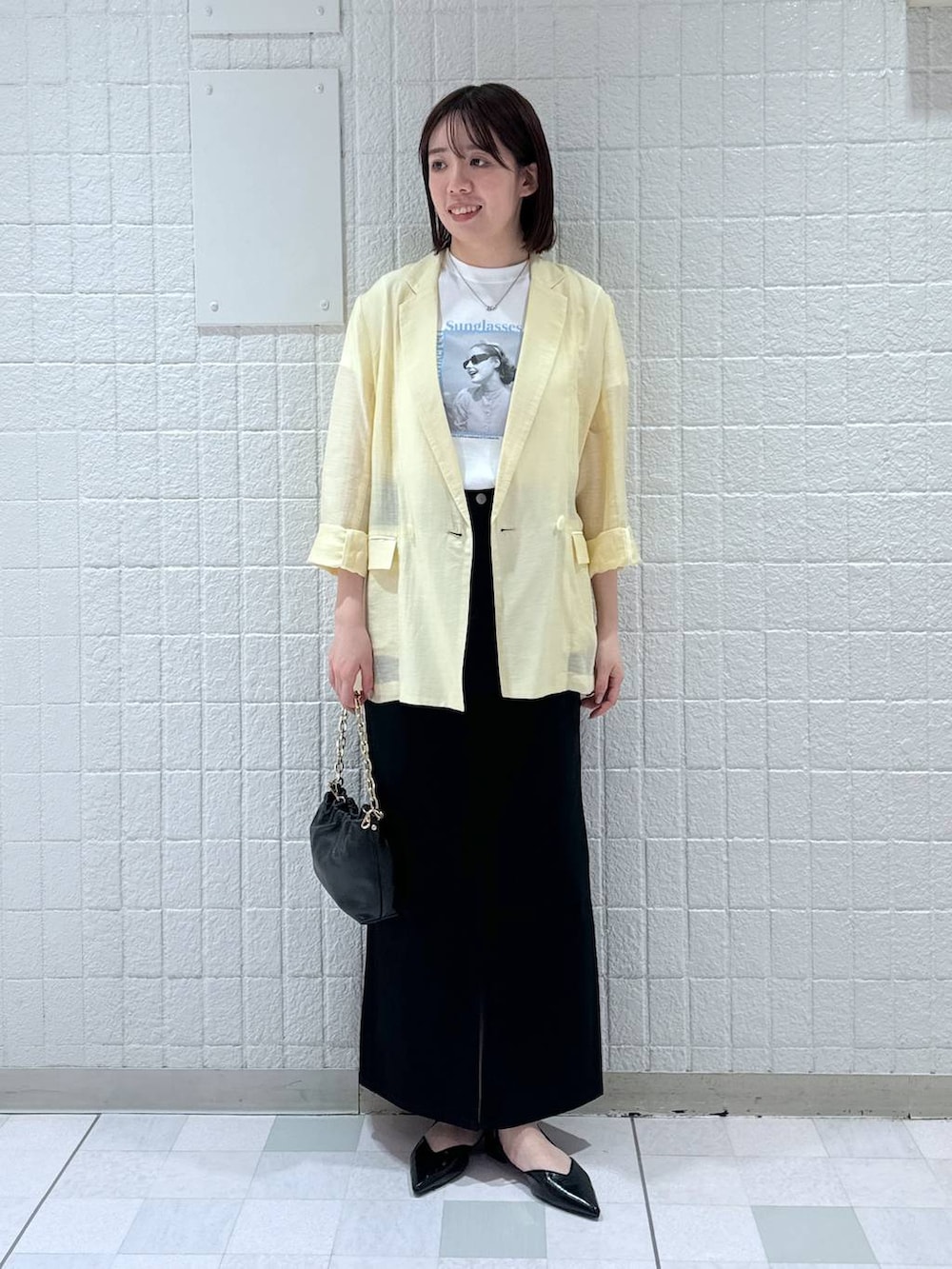 ブラック系のデニムスカート、イエロー系のテーラードジャケット、ブラック系のショルダーバッグを着用したレディースの春コーディネートの4枚目の写真