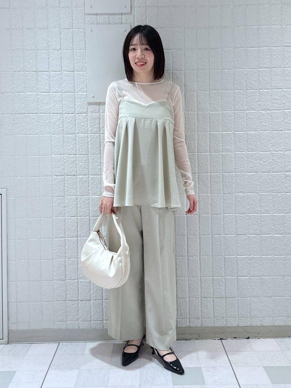 ホワイト系のハンドバッグ、ブラック系のパンプス、ベージュ系のキャミソールを着用したレディースの春コーディネートの4枚目の写真