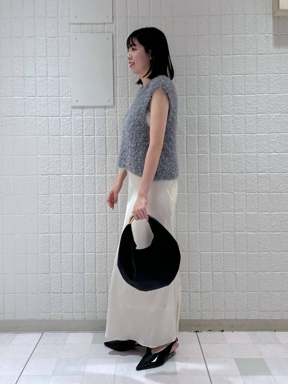 ホワイト系のスカート、ブラック系のハンドバッグ、ブラック系のパンプスを着用したレディースの秋コーディネートの2枚目の写真