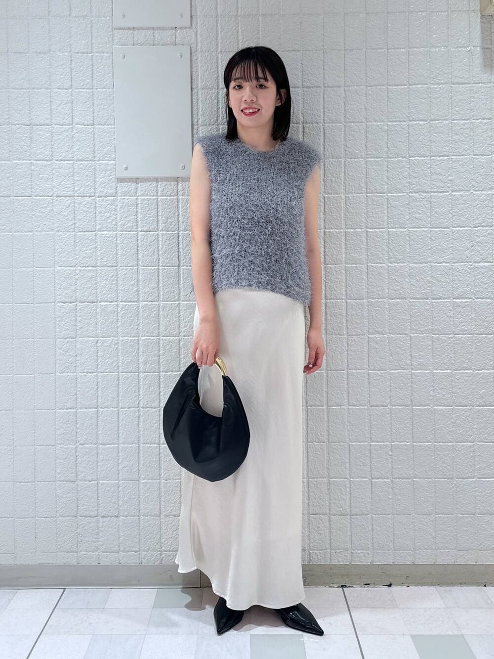 ホワイト系のスカート、ブラック系のハンドバッグ、ブラック系のパンプスを着用したレディースの秋コーディネートの4枚目の写真
