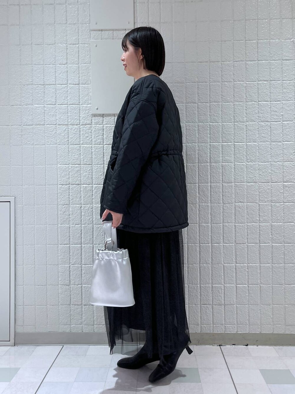 ブラック系のスカート、ブラック系のダウンジャケット/コート、ホワイト系のニット/セーターを着用したレディースの冬コーディネートの2枚目の写真