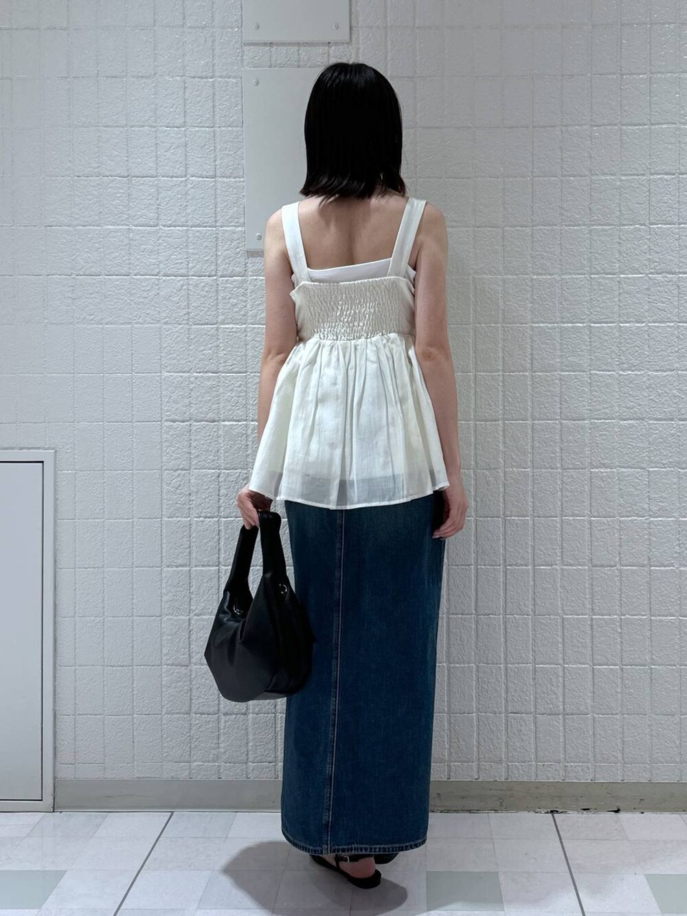 ブラック系のハンドバッグ、ブルー系のデニムスカート、ブラック系のサンダルを着用したレディースの夏コーディネートの3枚目の写真