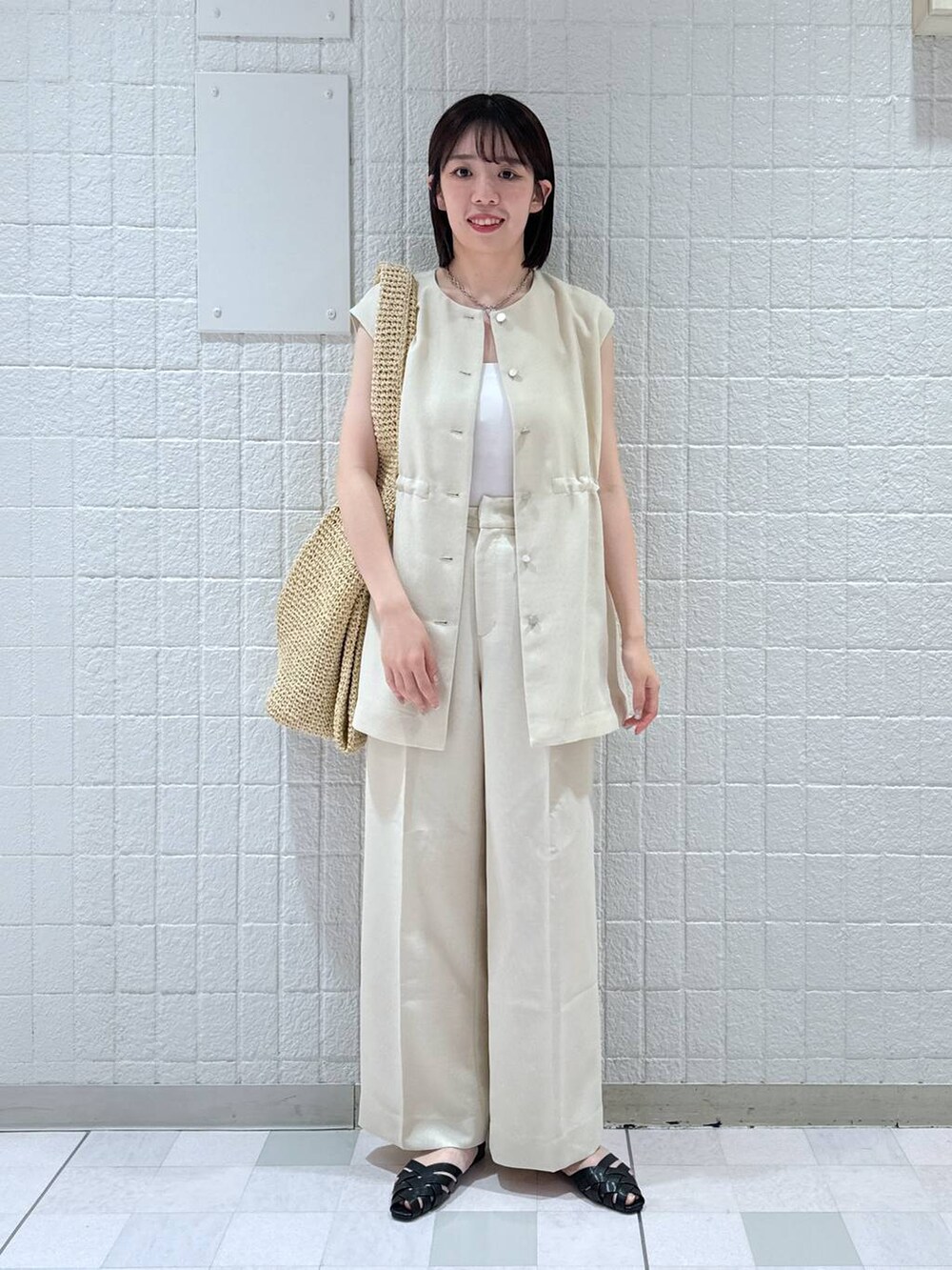 ベージュ系のトートバッグ、ホワイト系のベスト、ホワイト系のキャミソールを着用したレディースの夏コーディネートの4枚目の写真