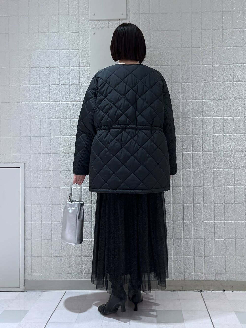 ブラック系のスカート、ブラック系のダウンジャケット/コート、ホワイト系のニット/セーターを着用したレディースの冬コーディネートの3枚目の写真