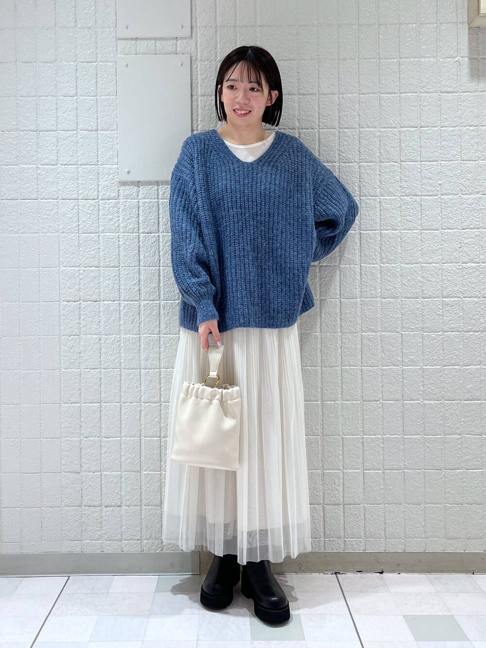 ホワイト系のスカート、ブルー系のニット/セーター、ブラック系のブーツを着用したレディースの冬コーディネートの4枚目の写真