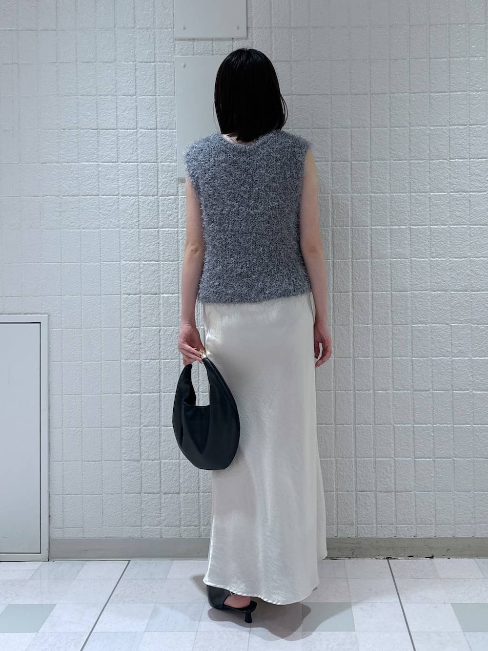 ホワイト系のスカート、ブラック系のハンドバッグ、ブラック系のパンプスを着用したレディースの秋コーディネートの3枚目の写真