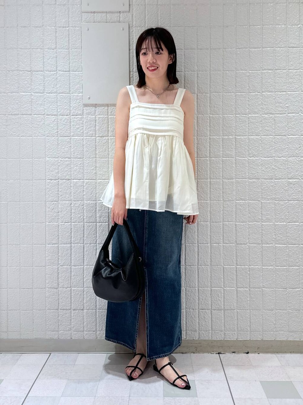 ブラック系のハンドバッグ、ブルー系のデニムスカート、ブラック系のサンダルを着用したレディースの夏コーディネートの4枚目の写真