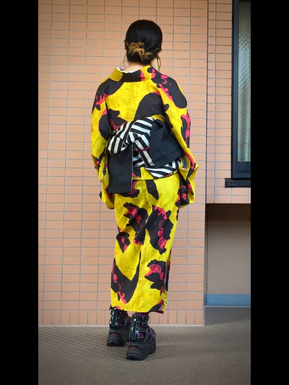 ピンク系のバッグ、ブラック系のサンダル、ゴールド系のヘアアクセサリーを着用したレディースの夏コーディネートの2枚目の写真