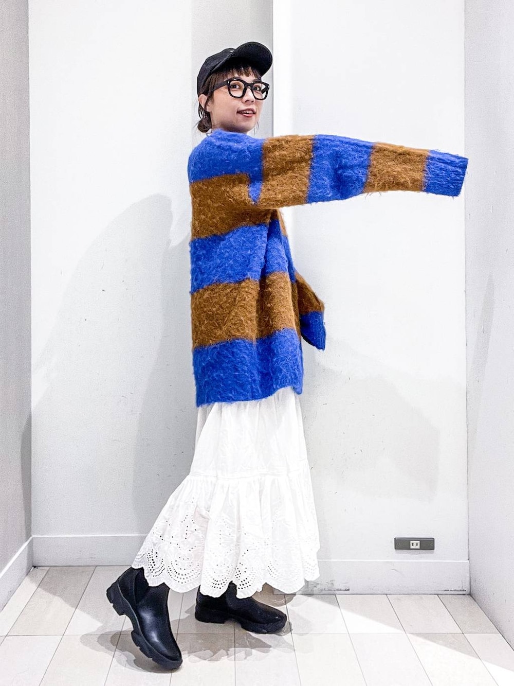 グレー系のステンカラーコート、ホワイト系のショルダーバッグ、ブルー系のニット/セーターを着用したレディースの冬コーディネートの9枚目の写真