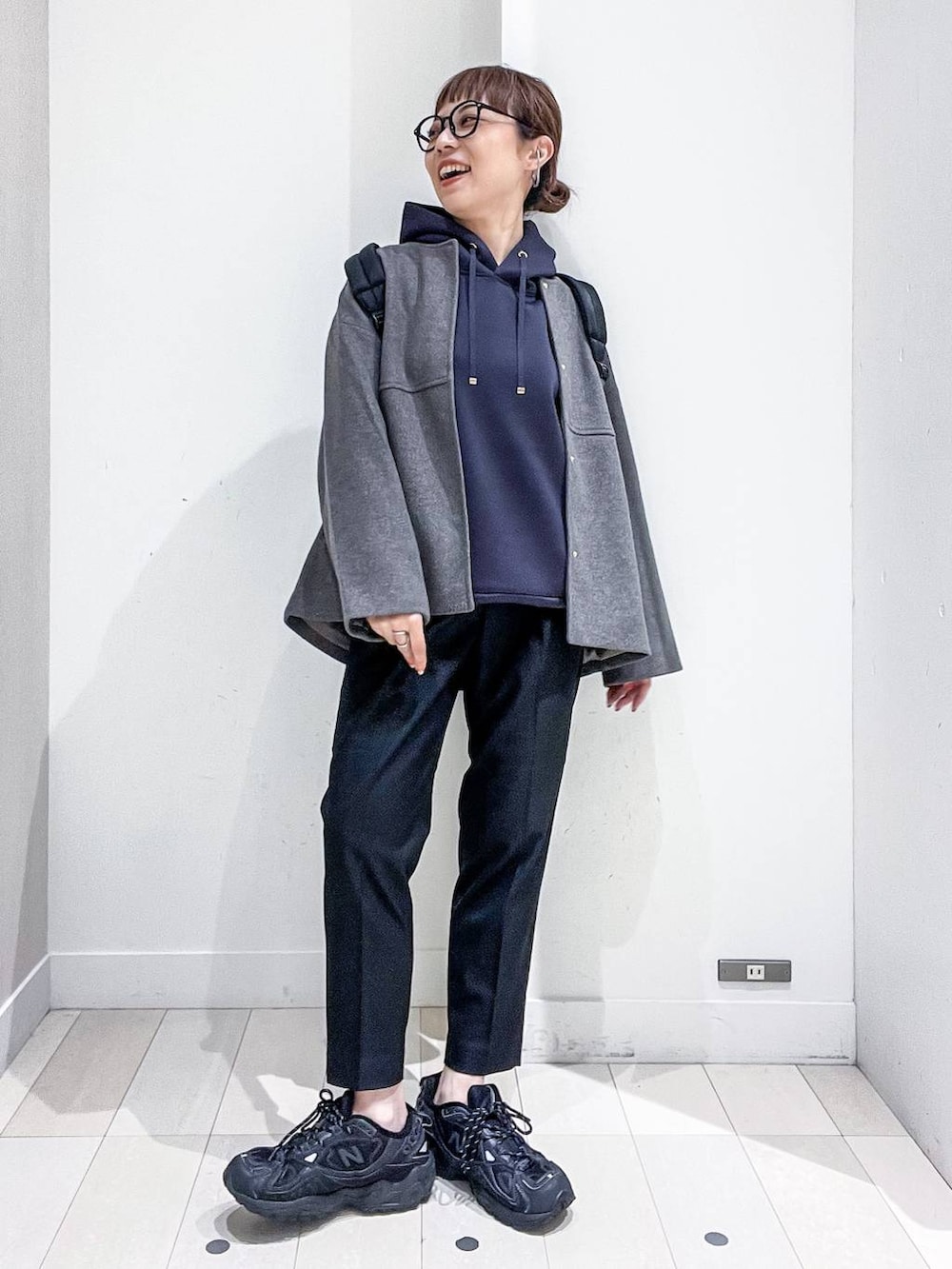 ブラック系のバックパック/リュック、グレー系のノーカラーコート、ブラック系のその他パンツを着用したレディースの秋コーディネートの2枚目の写真