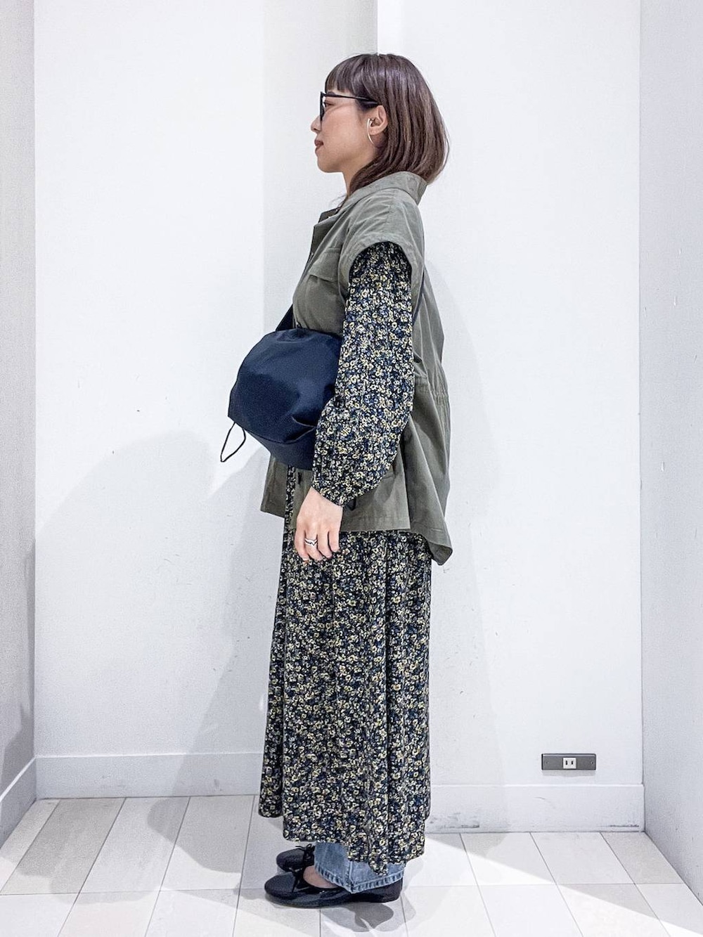 ブルー系のデニムパンツ、ブラック系のワンピース、ブラック系のバレエシューズを着用したレディースの秋コーディネートの3枚目の写真