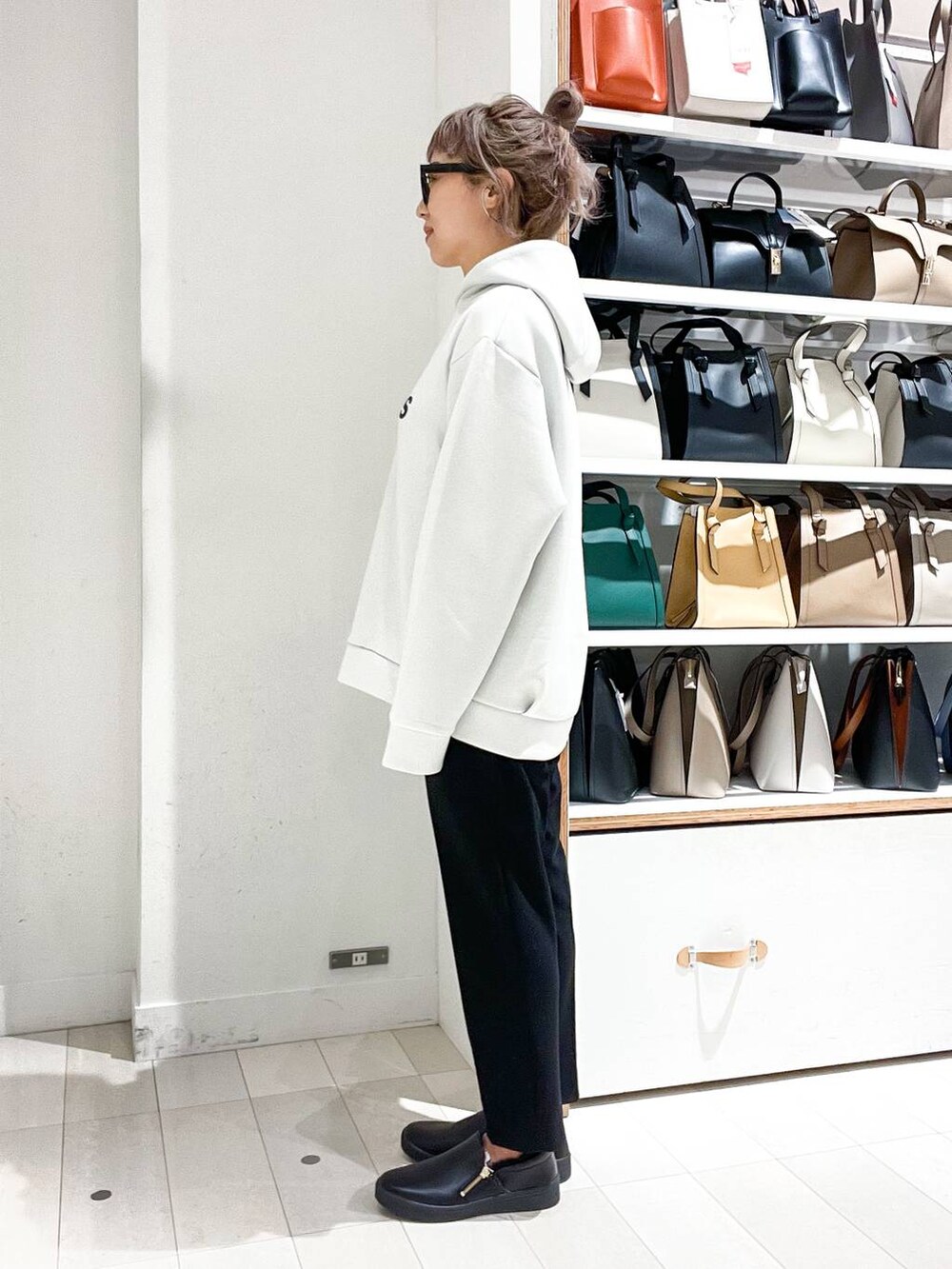 グレー系のノーカラーコート、ホワイト系のパーカー、グリーン系のショルダーバッグを着用したレディースの冬コーディネートの8枚目の写真