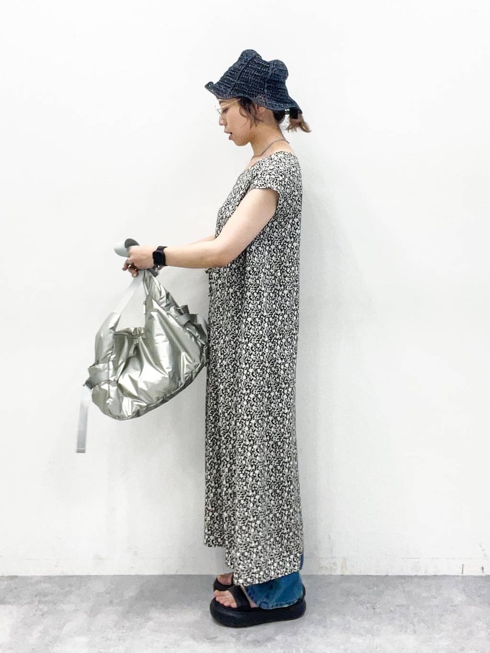 シルバー系のショルダーバッグ、ブルー系のデニムパンツ、ブラック系のサンダルを着用したレディースの夏コーディネートの3枚目の写真