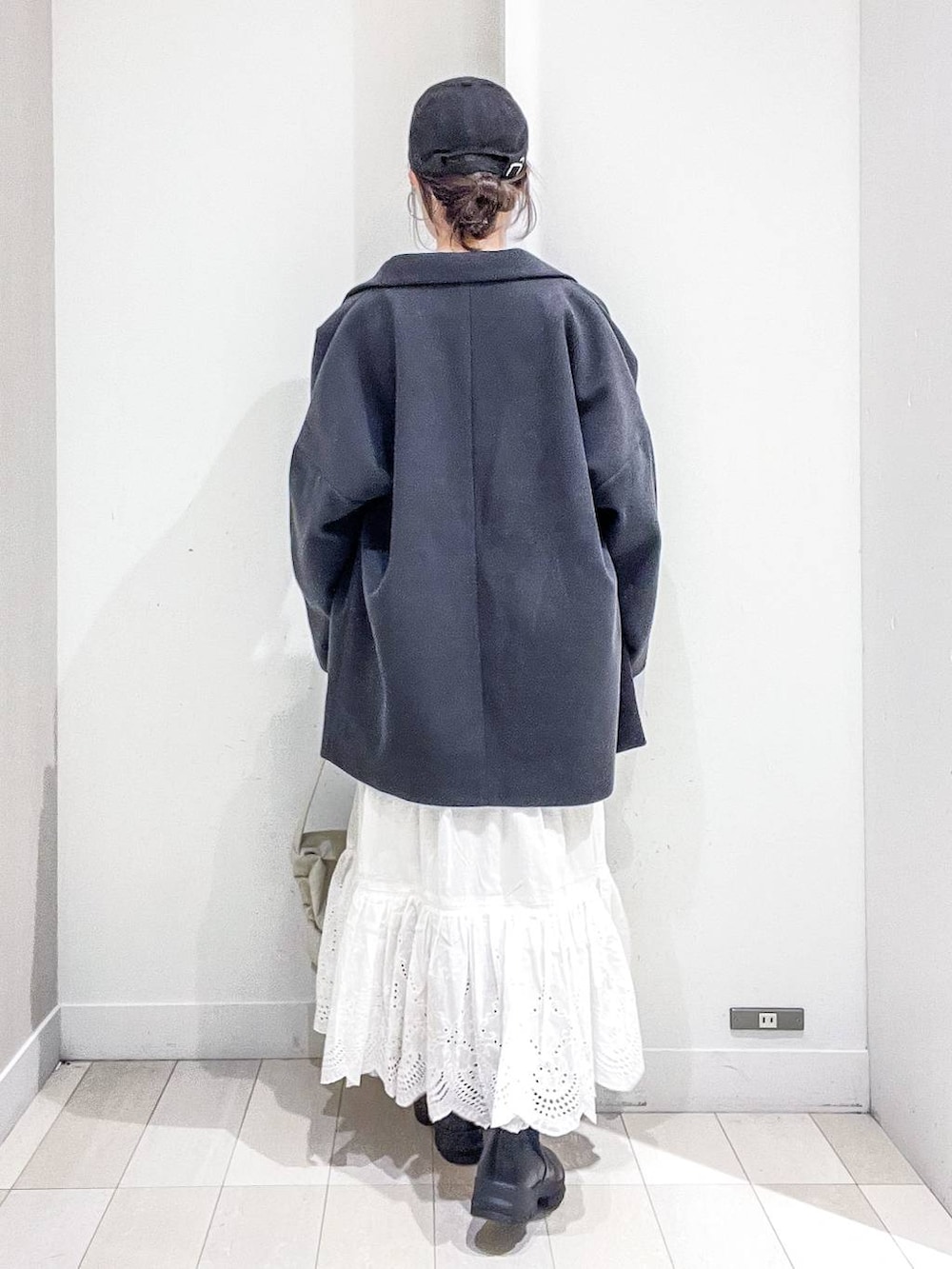 グレー系のステンカラーコート、ホワイト系のショルダーバッグ、ブルー系のニット/セーターを着用したレディースの冬コーディネートの4枚目の写真