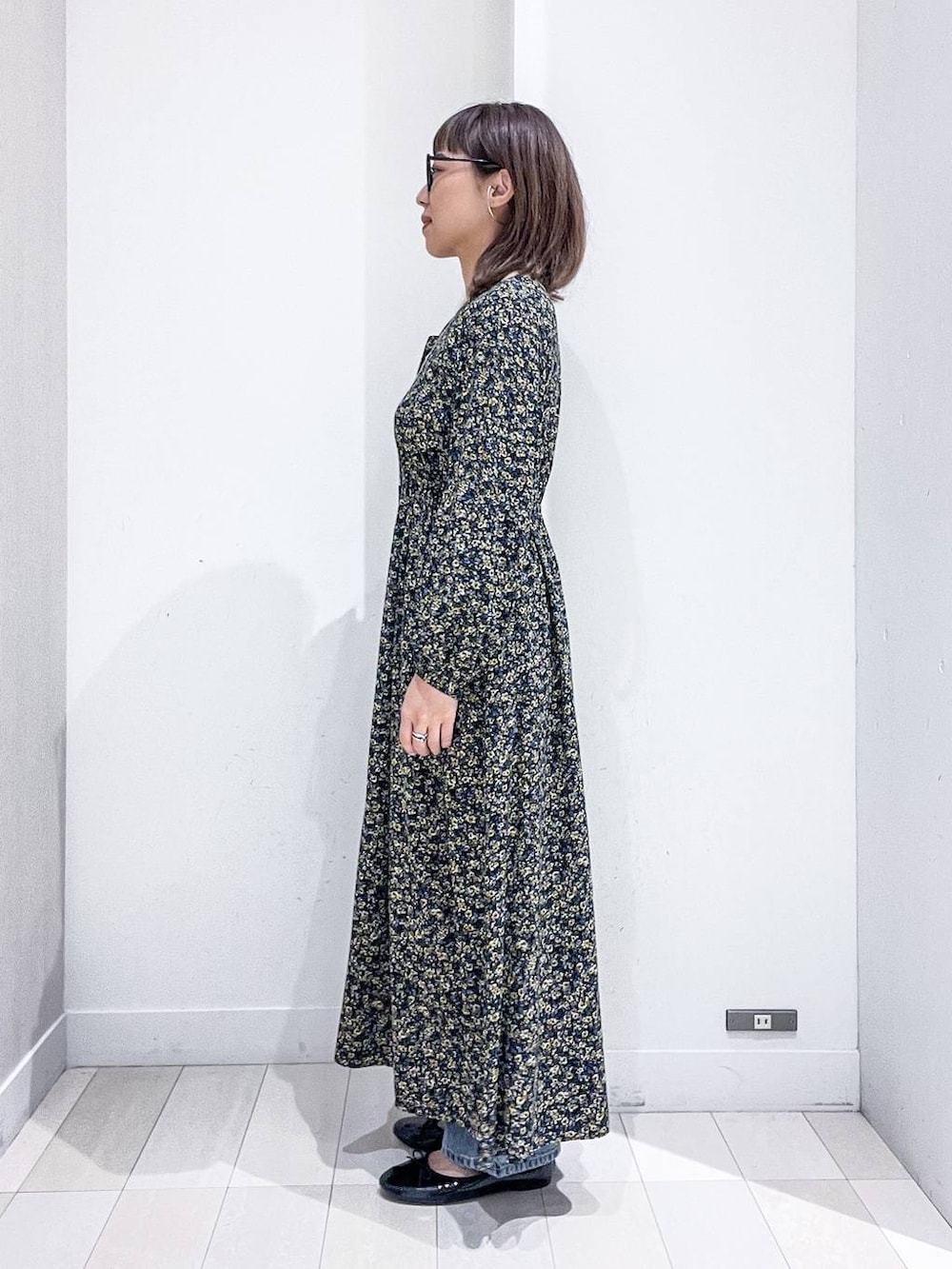 ブルー系のデニムパンツ、ブラック系のワンピース、ブラック系のバレエシューズを着用したレディースの秋コーディネートの7枚目の写真