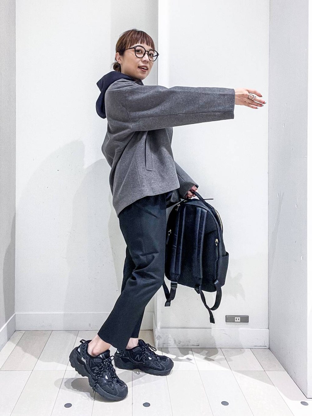 ブラック系のバックパック/リュック、グレー系のノーカラーコート、ブラック系のその他パンツを着用したレディースの秋コーディネートの5枚目の写真