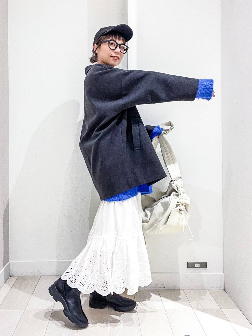 グレー系のステンカラーコート、ホワイト系のショルダーバッグ、ブルー系のニット/セーターを着用したレディースの冬コーディネートの5枚目の写真