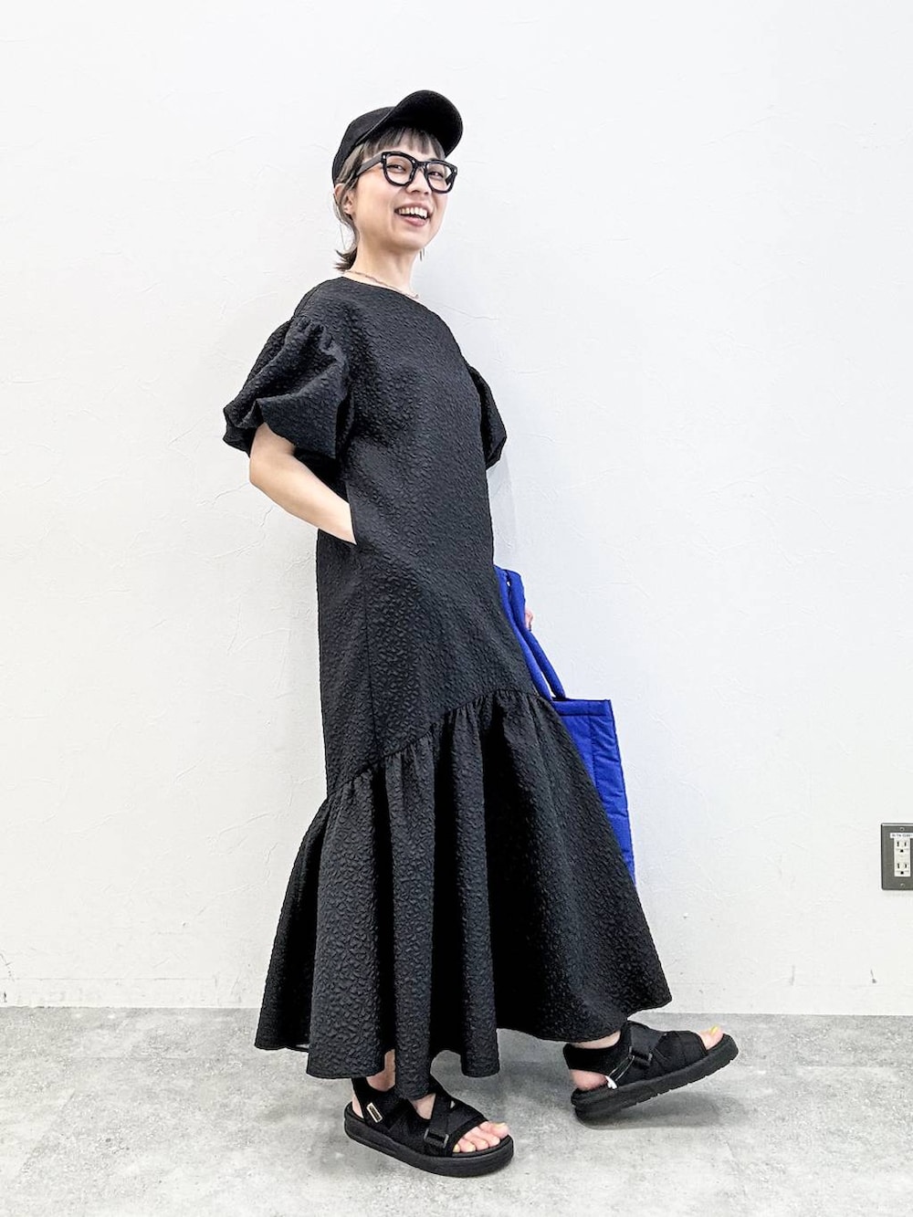 ブラック系のサンダル、ブルー系のトートバッグ、ブラック系のキャップを着用したレディースの春コーディネートの6枚目の写真