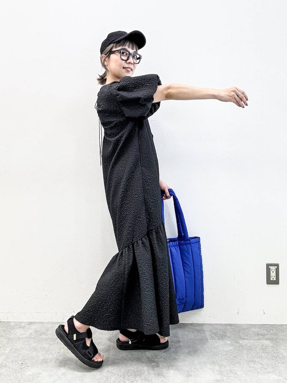 ブラック系のサンダル、ブルー系のトートバッグ、ブラック系のキャップを着用したレディースの春コーディネートの5枚目の写真