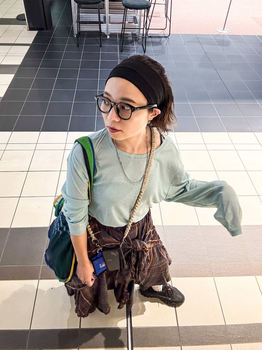 グリーン系のTシャツ/カットソー、ブラウン系のスカート、ブラック系のヘアバンドを着用したレディースの秋コーディネートの2枚目の写真