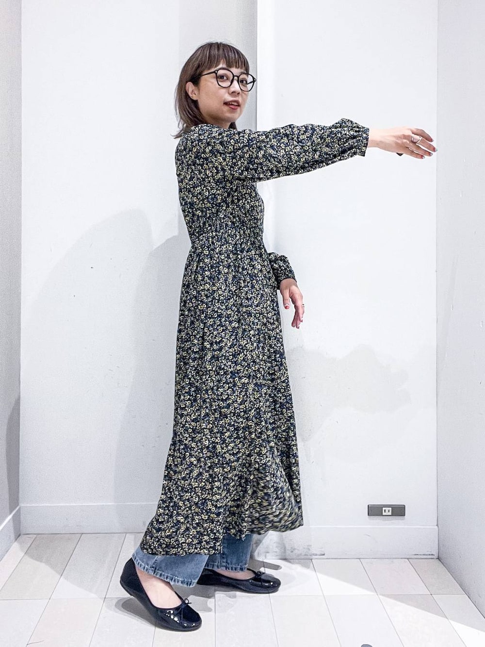 ブルー系のデニムパンツ、ブラック系のワンピース、ブラック系のバレエシューズを着用したレディースの秋コーディネートの9枚目の写真