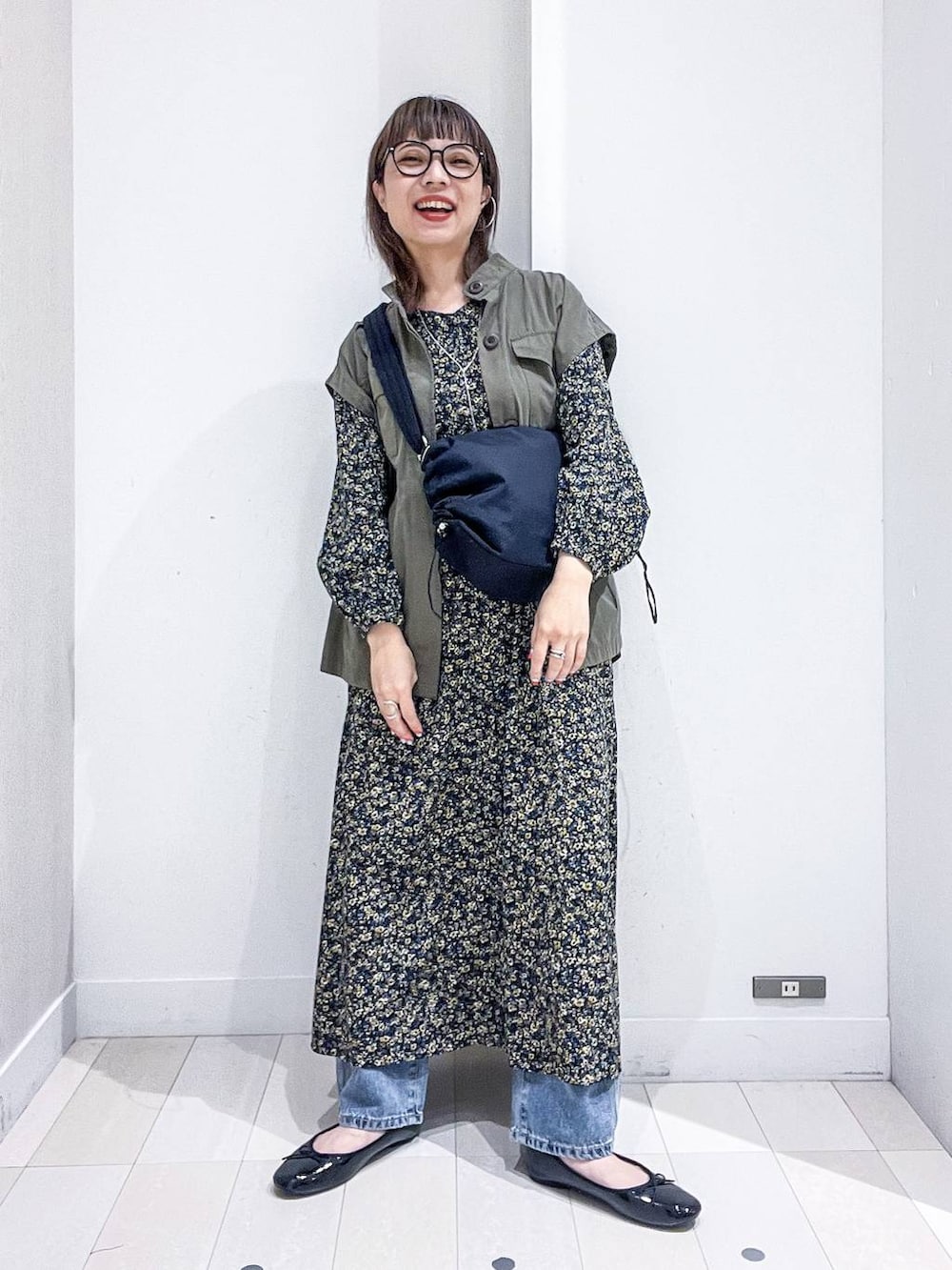 ブルー系のデニムパンツ、ブラック系のワンピース、ブラック系のバレエシューズを着用したレディースの秋コーディネートの2枚目の写真