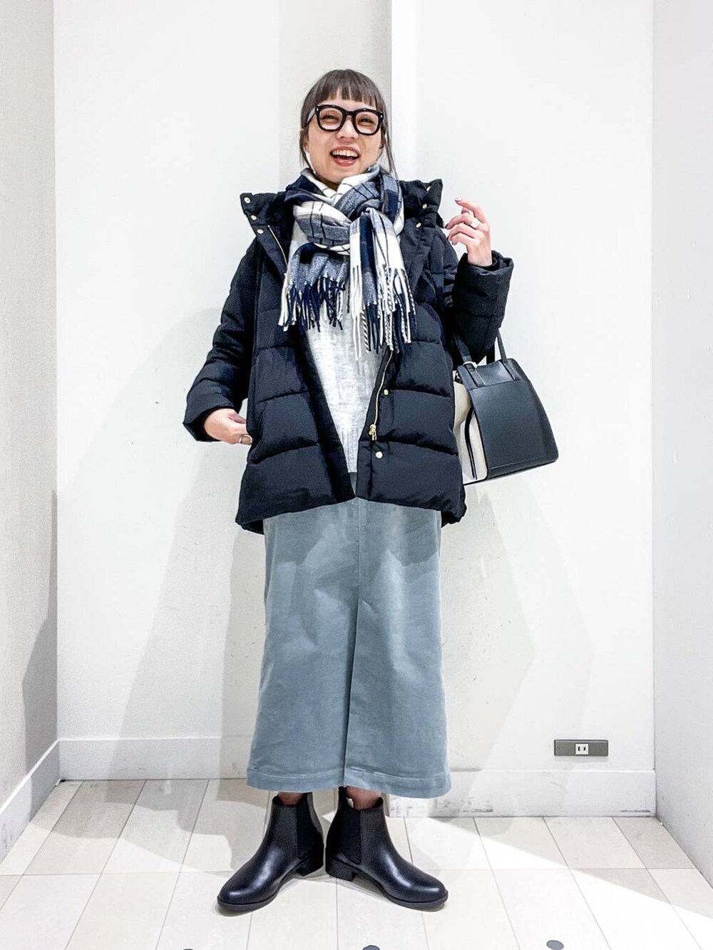 ブラック系のショルダーバッグ、ブラック系のダウンジャケット/コート、グリーン系のスカートを着用したレディースの冬コーディネートの2枚目の写真