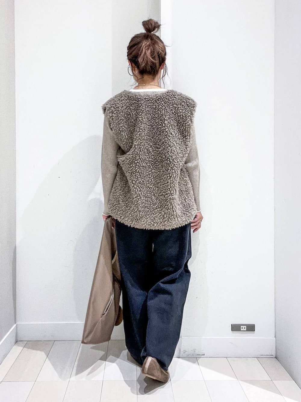 ベージュ系のニット/セーター、ブラック系のデニムパンツ、ベージュ系のトートバッグを着用したレディースの秋コーディネートの4枚目の写真