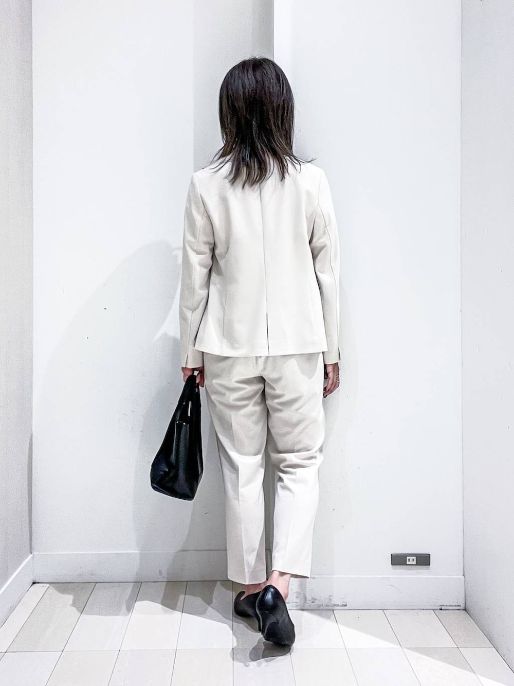 ブラック系のパンプス、ホワイト系のスーツジャケット、ホワイト系のシャツ/ブラウスを着用したレディースの冬コーディネートの4枚目の写真