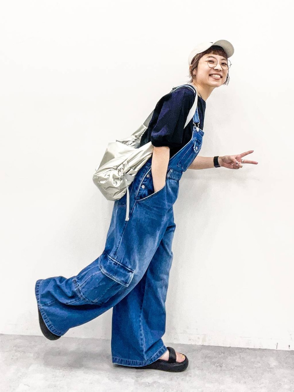 シルバー系のショルダーバッグ、ブラック系のTシャツ/カットソー、ブルー系のサロペット/オーバーオールを着用したレディースの夏コーディネートの6枚目の写真