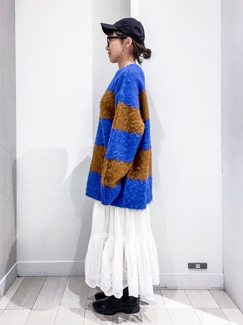 グレー系のステンカラーコート、ホワイト系のショルダーバッグ、ブルー系のニット/セーターを着用したレディースの冬コーディネートの7枚目の写真