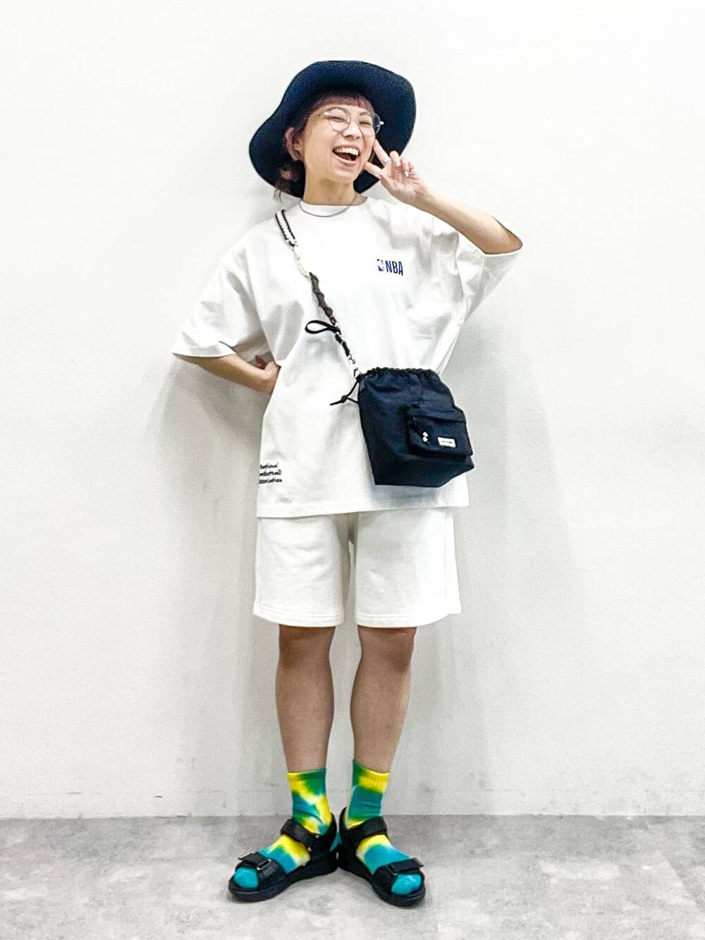 ブラック系のサンダル、ブラック系のショルダーバッグ、ホワイト系のTシャツ/カットソーを着用したレディースの夏コーディネートの2枚目の写真