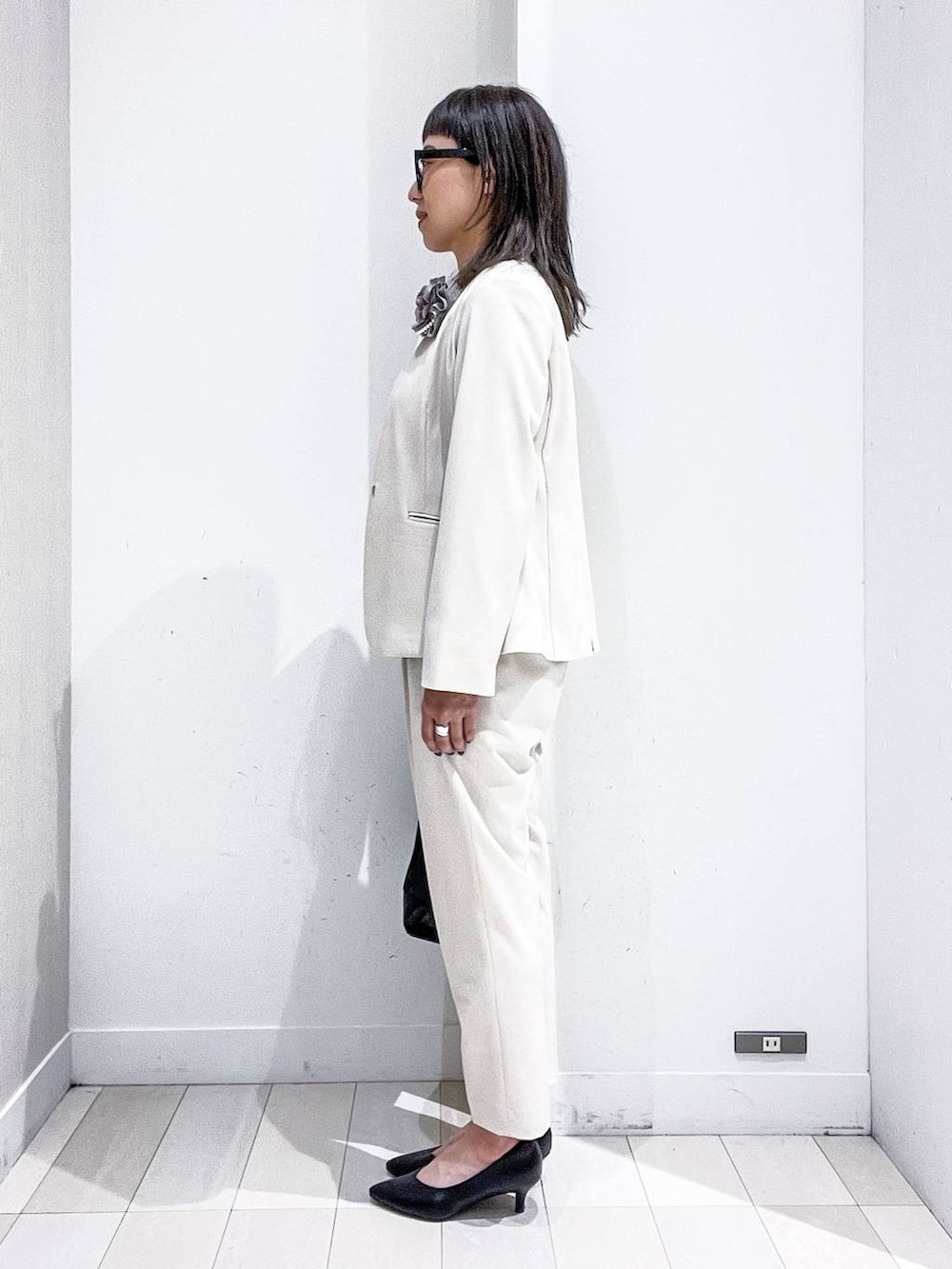 ブラック系のパンプス、ホワイト系のスーツジャケット、ホワイト系のシャツ/ブラウスを着用したレディースの冬コーディネートの3枚目の写真