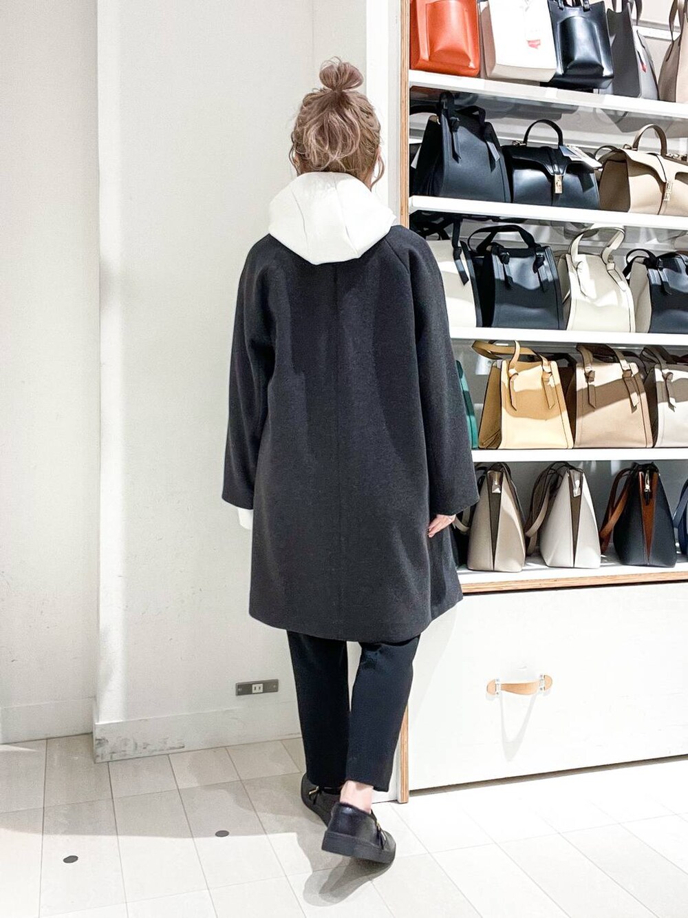 グレー系のノーカラーコート、ホワイト系のパーカー、グリーン系のショルダーバッグを着用したレディースの冬コーディネートの6枚目の写真