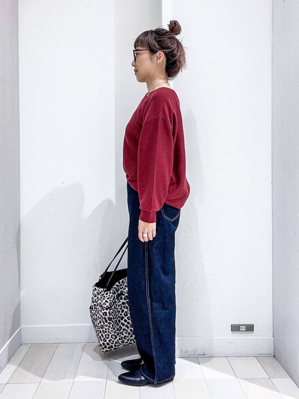 ブラック系のパンプス、レッド系のニット/セーター、ブルー系のデニムパンツを着用したレディースの秋コーディネートの3枚目の写真