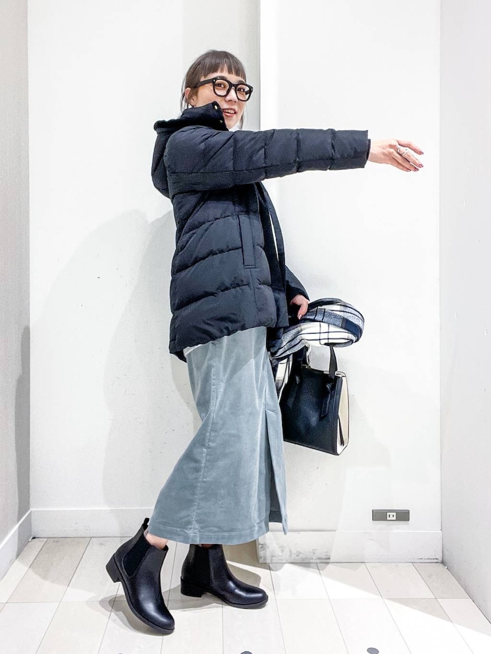 ブラック系のショルダーバッグ、ブラック系のダウンジャケット/コート、グリーン系のスカートを着用したレディースの冬コーディネートの5枚目の写真