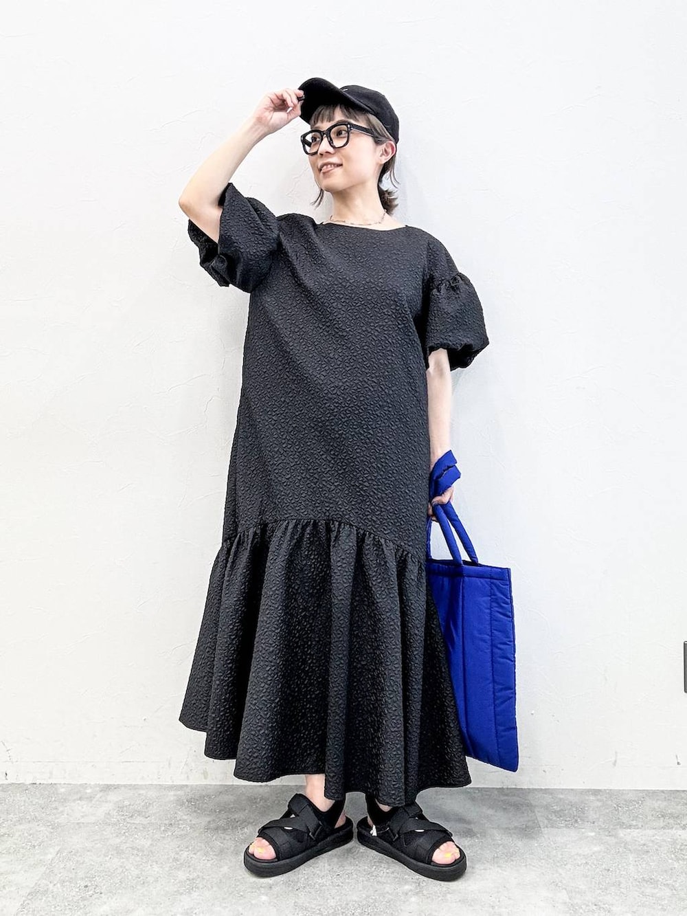 ブラック系のサンダル、ブルー系のトートバッグ、ブラック系のキャップを着用したレディースの春コーディネートの2枚目の写真