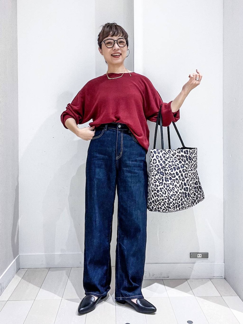 ブラック系のパンプス、レッド系のニット/セーター、ブルー系のデニムパンツを着用したレディースの秋コーディネートの2枚目の写真