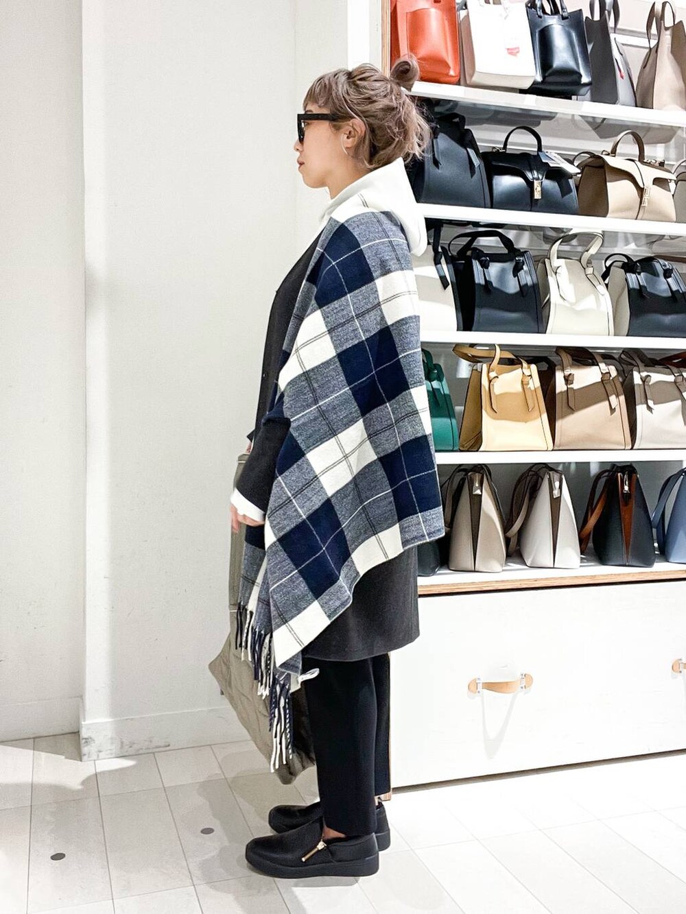 グレー系のノーカラーコート、ホワイト系のパーカー、グリーン系のショルダーバッグを着用したレディースの冬コーディネートの2枚目の写真