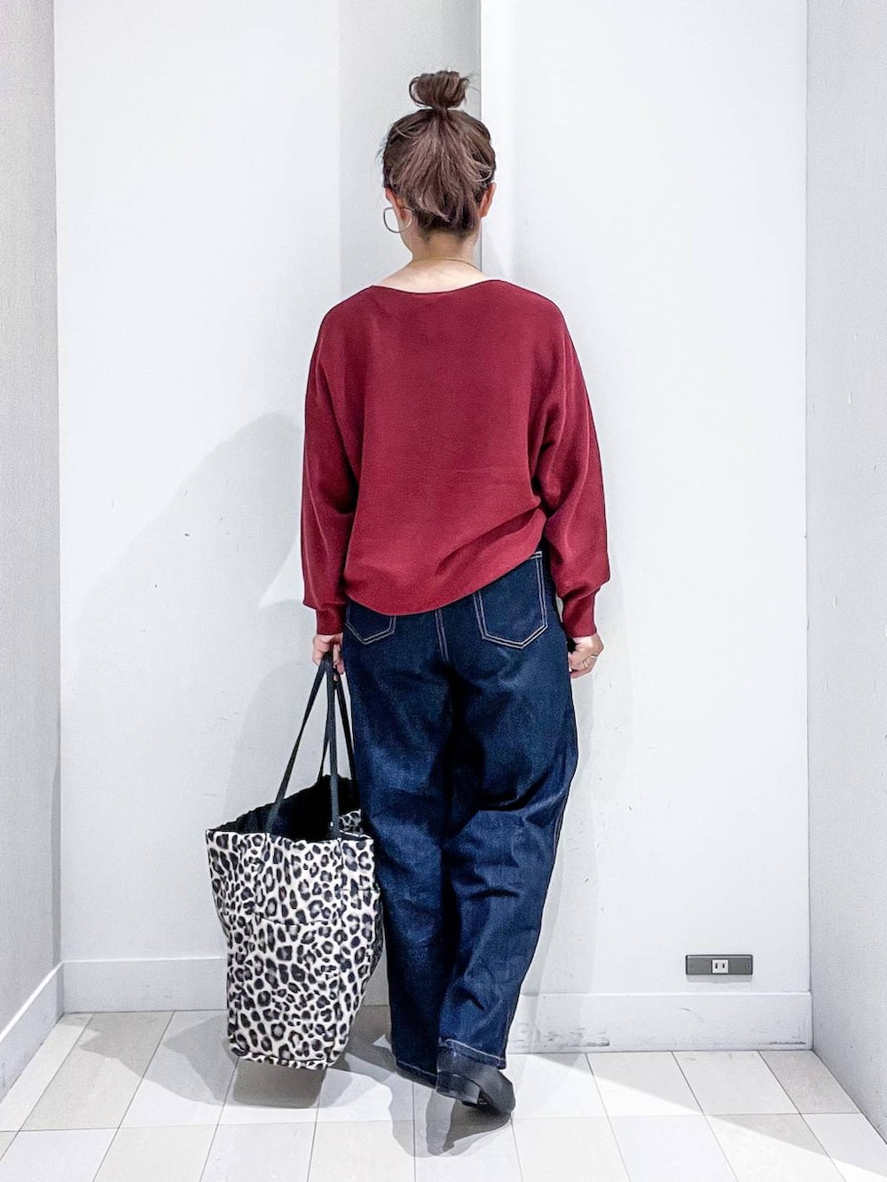 ブラック系のパンプス、レッド系のニット/セーター、ブルー系のデニムパンツを着用したレディースの秋コーディネートの4枚目の写真