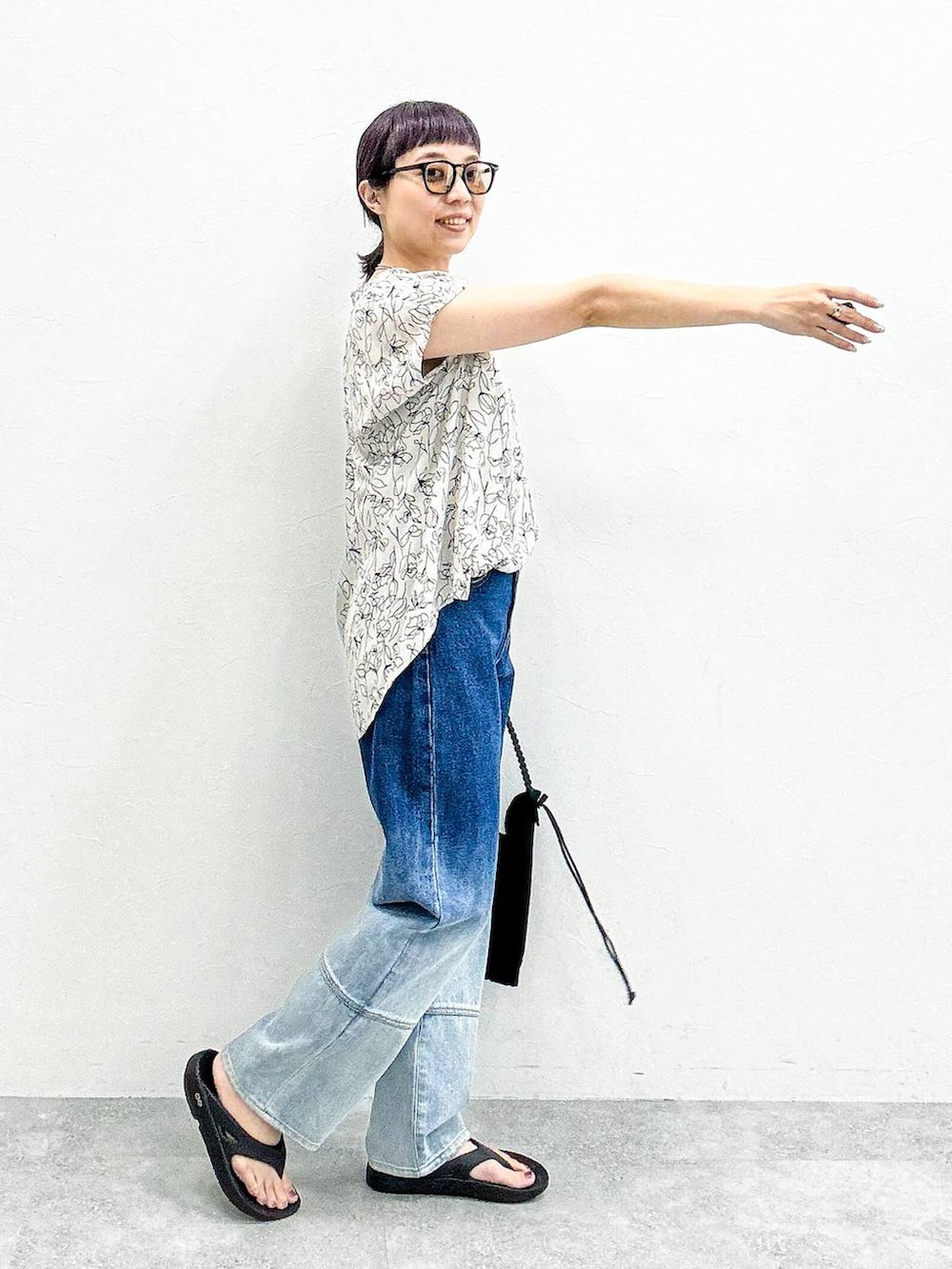 ブラック系のショルダーバッグ、ブルー系のデニムパンツ、ブラック系のサンダルを着用したレディースの夏コーディネートの5枚目の写真