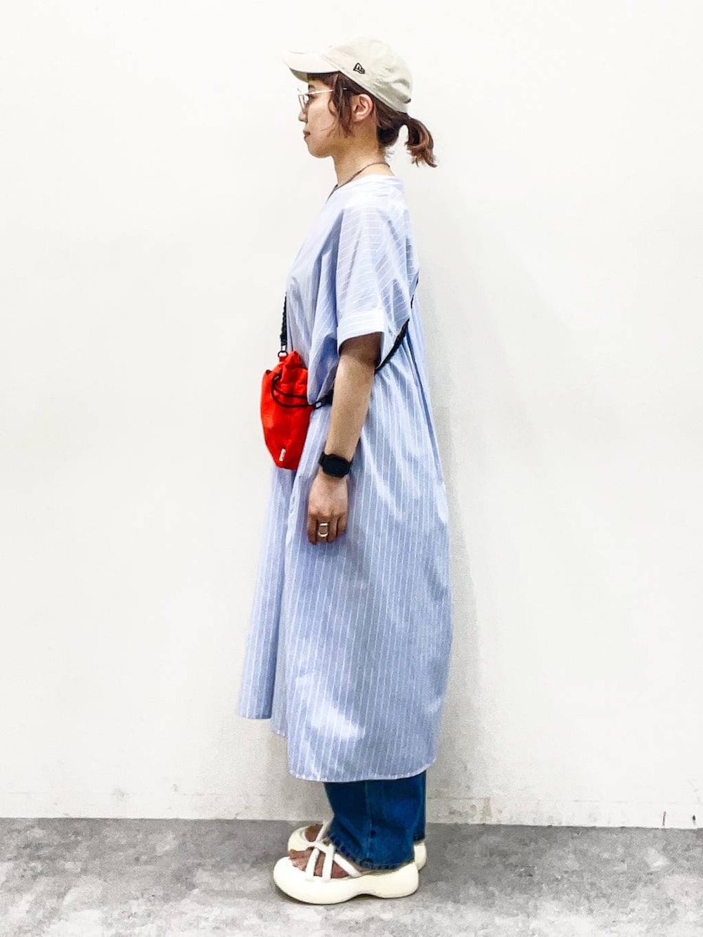 ホワイト系のサンダル、オレンジ系のショルダーバッグ、ブルー系のデニムパンツを着用したレディースの夏コーディネートの3枚目の写真