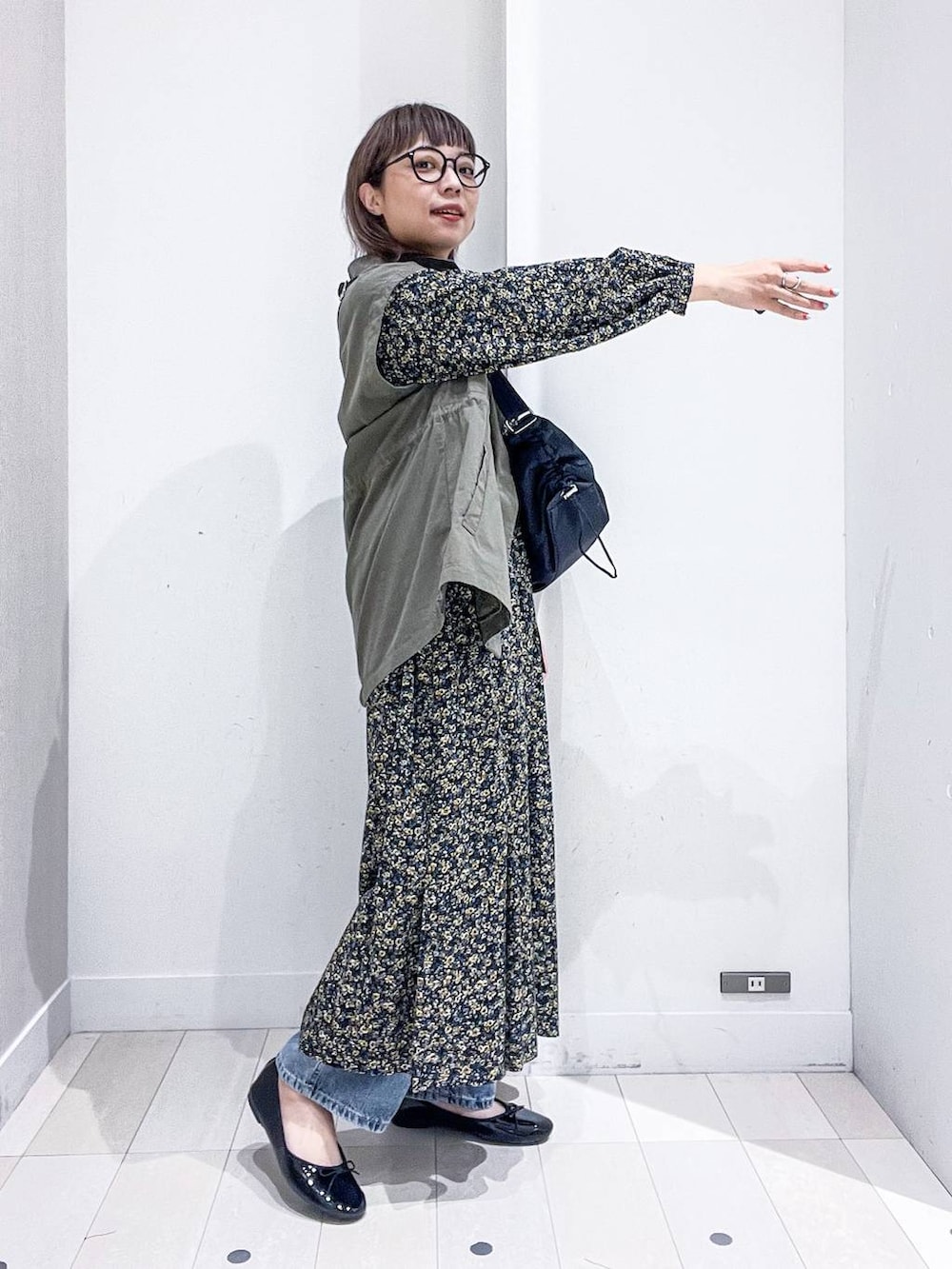 ブルー系のデニムパンツ、ブラック系のワンピース、ブラック系のバレエシューズを着用したレディースの秋コーディネートの5枚目の写真