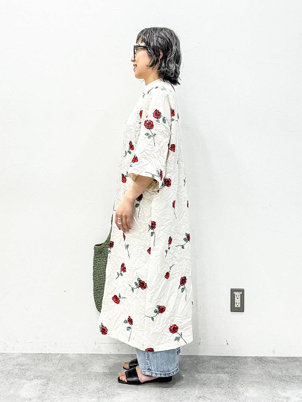 グリーン系のショルダーバッグ、ブラック系のサンダル、ブルー系のデニムパンツを着用したレディースの春コーディネートの3枚目の写真